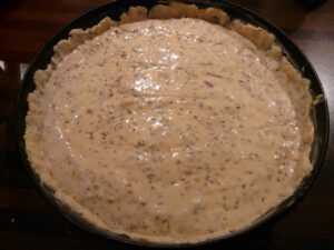Torta salata con fondo molliccio, pasta bucherellata e cotta "in bianco" prima della farcitura.