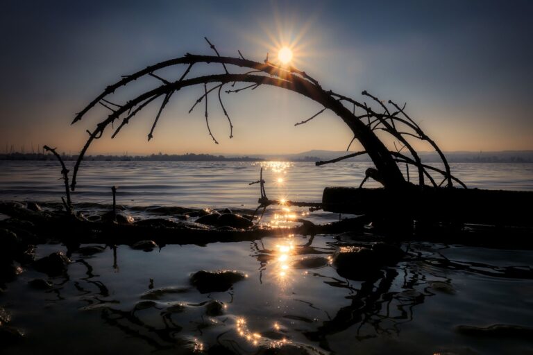 Tramonto infuocato sul lago Trasimeno, con le isole in primo piano e il cielo colorato di sfumature calde.