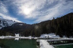 Vista panoramica del lago di Braies, circondato da monti, con turisti che esplorano la riva affollata.