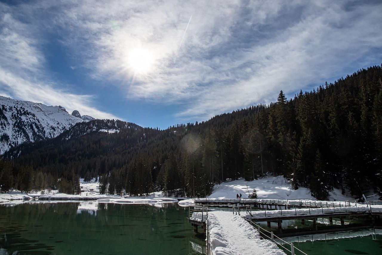 Lago di Carezza con il Latemar che si riflette nell'acqua cristallina, circondato da boschi delle Dolomiti.