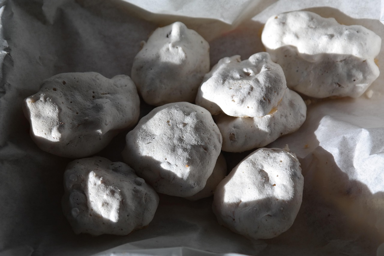 Meringhe bianche su una teglia, forno a bassa temperatura con sportello socchiuso.